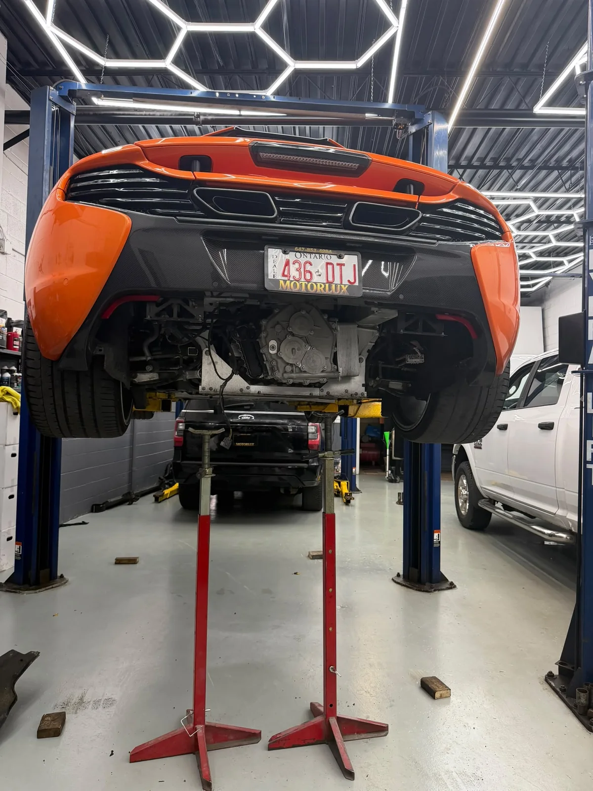 Orange performance car on a vehicle lift at Motorlux Auto Repairs